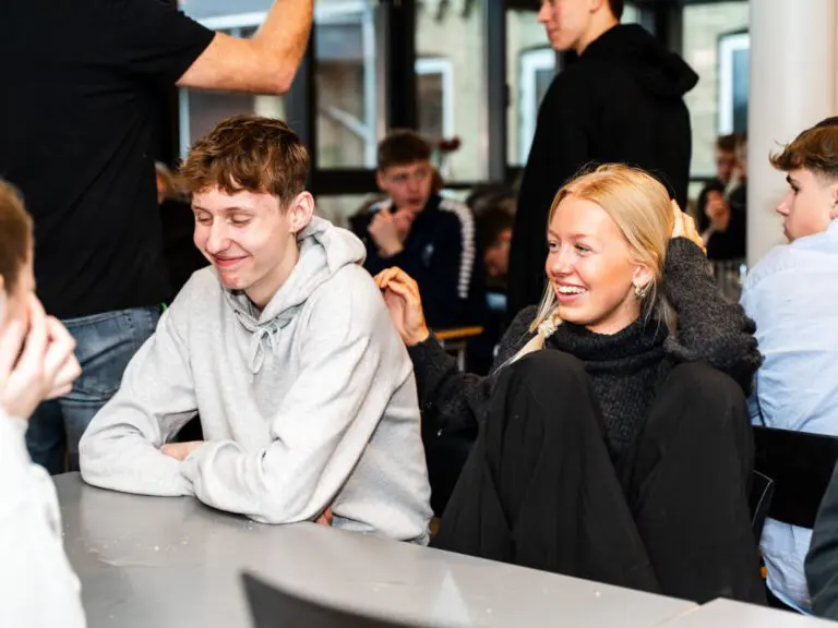 To elever sidder og griner i spisesalen på efterskole