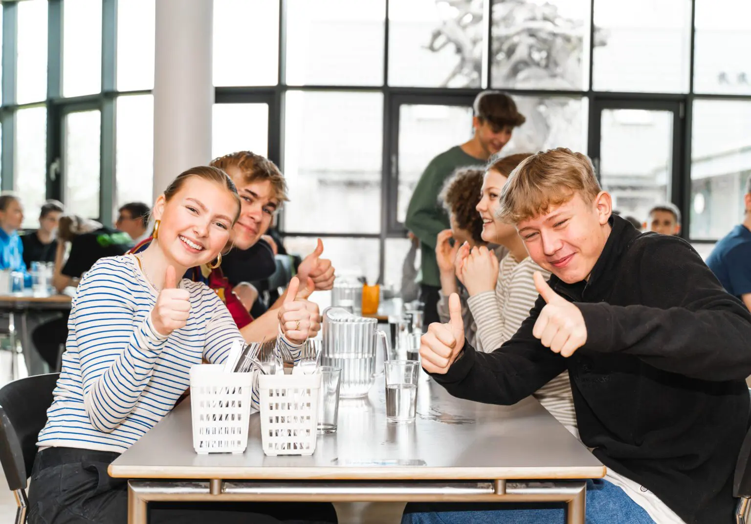 Elever sidder i spisesalen og drikker vand