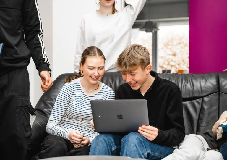 Dreng og pige sidder i en sofa og kigger på computer på efterskole