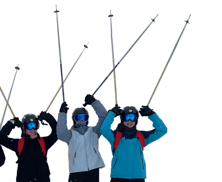 Tre piger med ski og skistave oppe i luften på efterskole