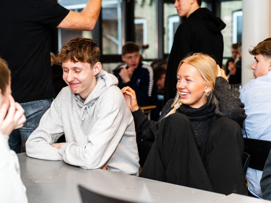 To elever sidder og griner i spisesalen på efterskole