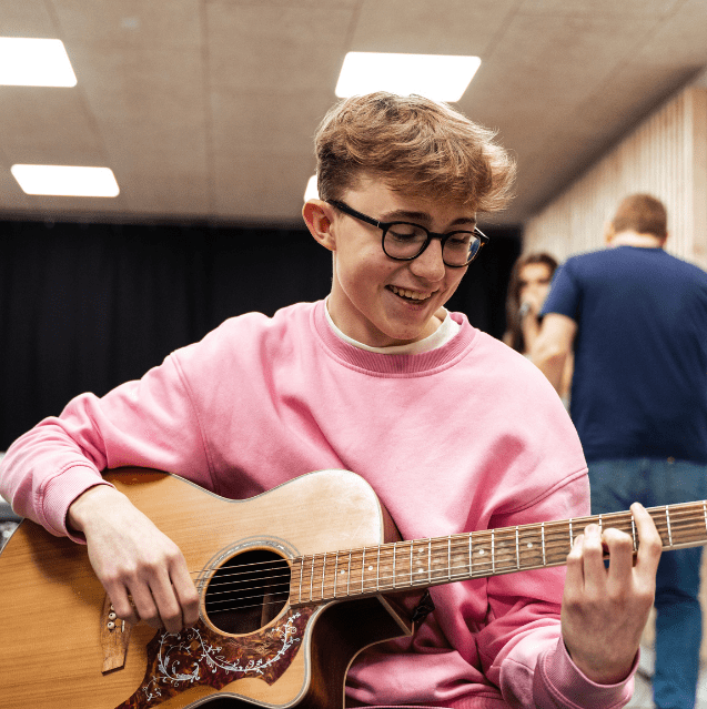 Dreng spiller guitar på musiklinje på efterskole