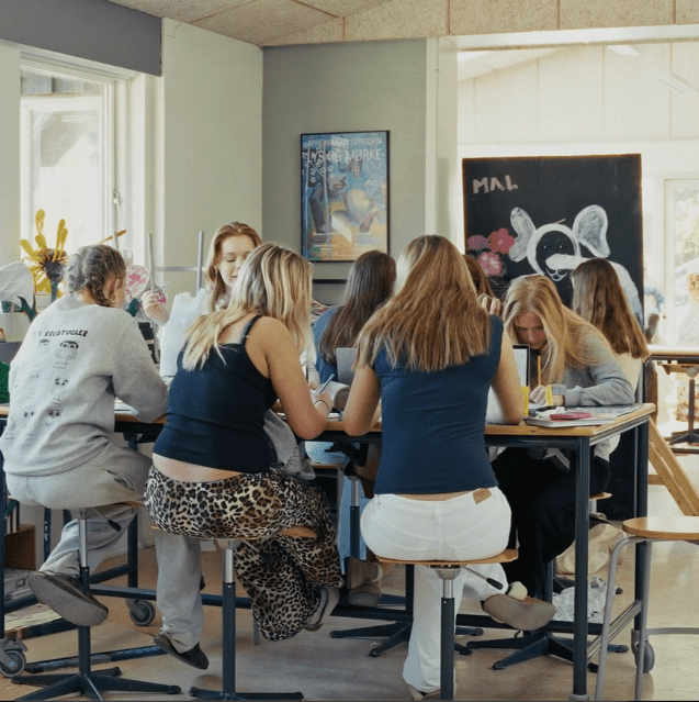 Elever på kunst linje på efterskole arbejder sammen ved højt bord